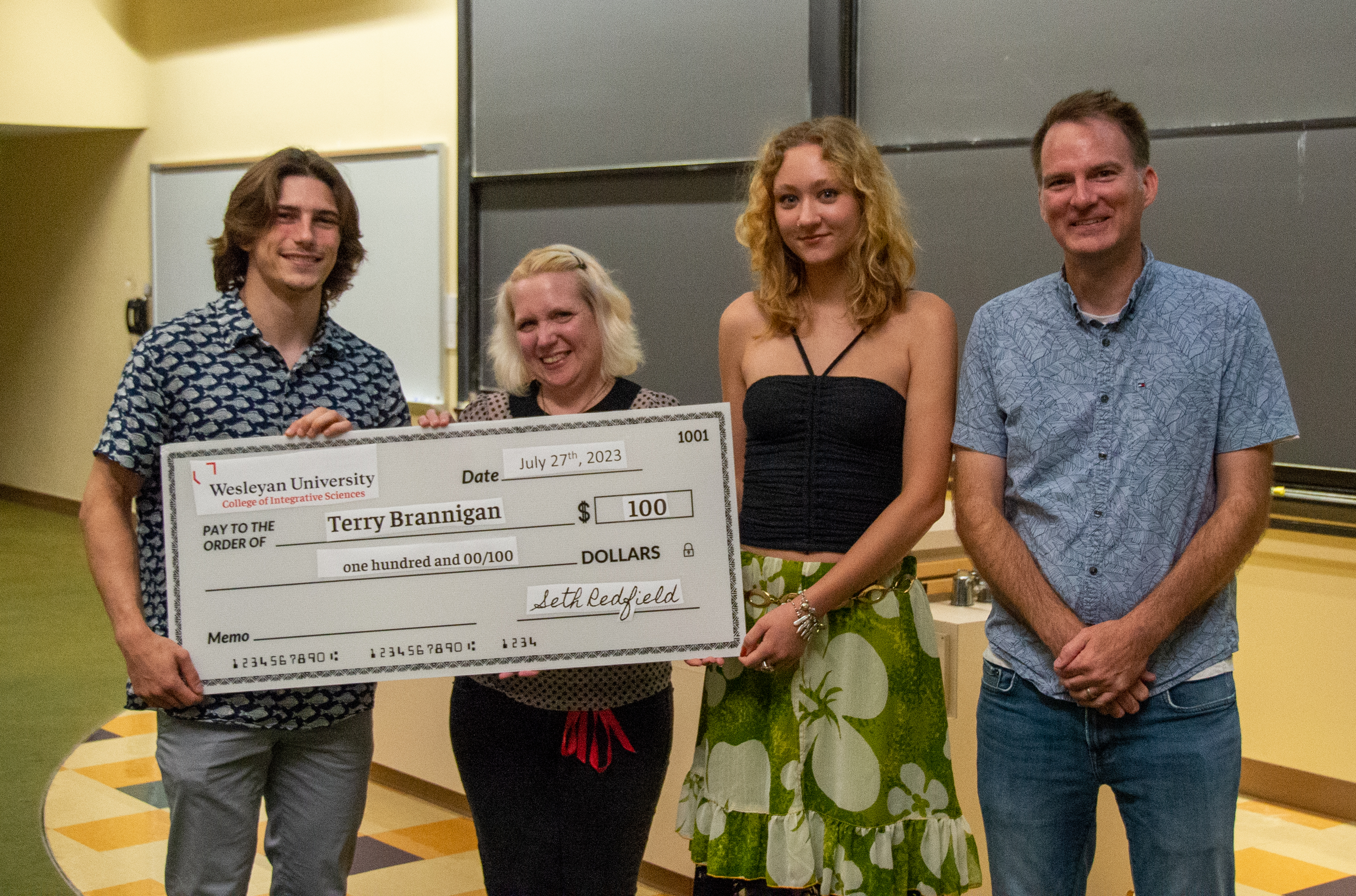 prize winners Terry Brannigan and Maya Alicki receive a giant check from Director Seth Redfield and Program Coordinator Anika Dane